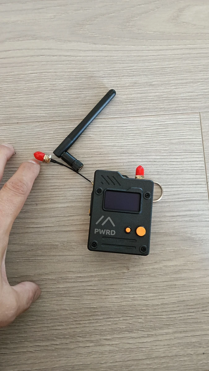 unboxing del dispositivo radio LoRa portatile con antenna scollegata, su un tavolo di legno chiaro